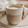 Keramikbecher „Hab einen tollen Tag“ in Beige und Weiß mit Herz, gefüllt mit Kaffee