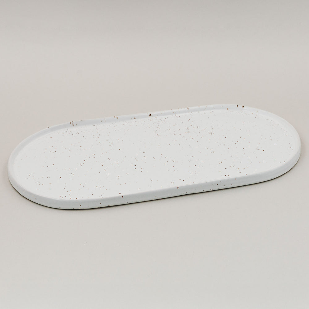 Weiße ovale Servierplatte Calma groß mit Sprenkelmuster auf hellem Hintergrund