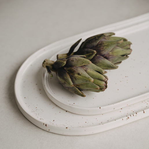 Servierplatten Calma dekorativ gestapelt mit zwei Artischocken – natürlich und stilvoll