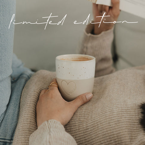 Keramikbecher Mama mit Herzdetail, gefüllt mit Kaffee, gemütlich auf Sofa