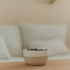 Keramikschale mit Herz in Beige und Weiß, gefüllt mit Heidelbeeren auf einem Holztisch