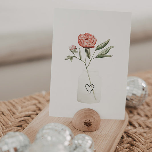 Postkarte mit Blumenmotiv in einer kleinen halbrunden Kartenhalterung aus Holz mit Daisy-Gravur.