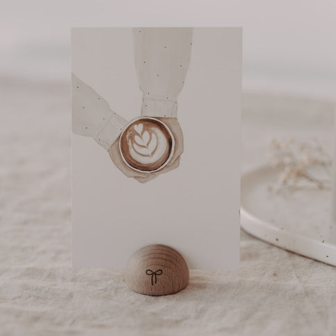 Kartenständer aus Holz in Halbrundform mit Schleife, hält Karte mit Latte Art auf Leinentisch