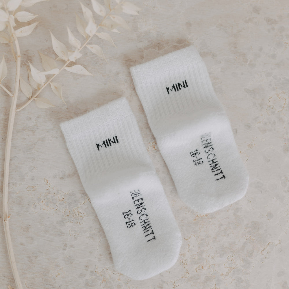 Zwei „MINI“-Socken von unten mit „EULENSCHNITT 16/18“-Größe sichtbar auf hellem Natursteinboden