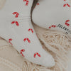 Nahaufnahme der weißen Zuckerstangen-Socken mit rotem Muster – detailreicher Blick auf das Strickmotiv.