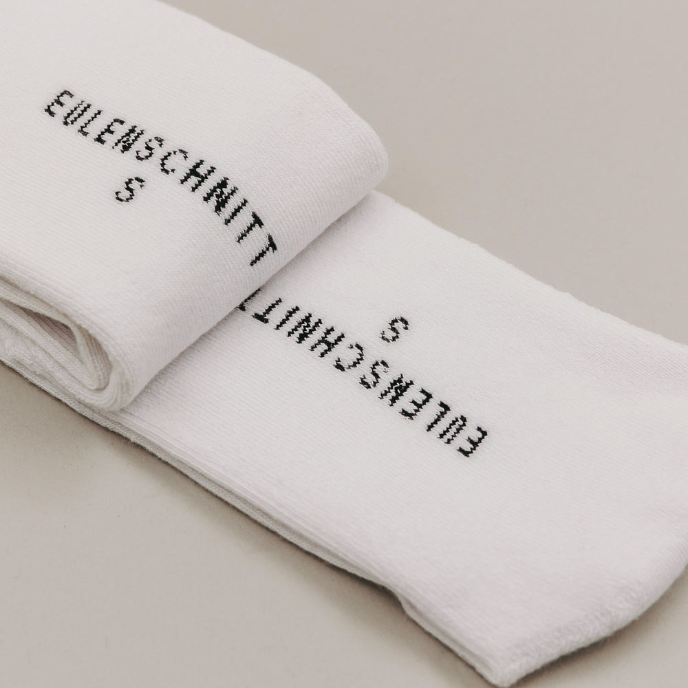 Gefaltete weiße Socken mit Schriftzug „Ich lieb’s“ in minimalistischer Produktdarstellung