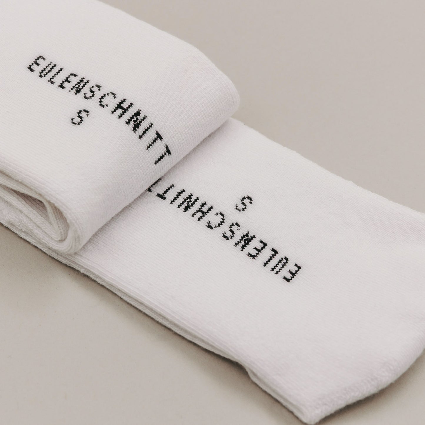 Gefaltete weiße Socken mit Schriftzug „Ich lieb’s“ in minimalistischer Produktdarstellung
