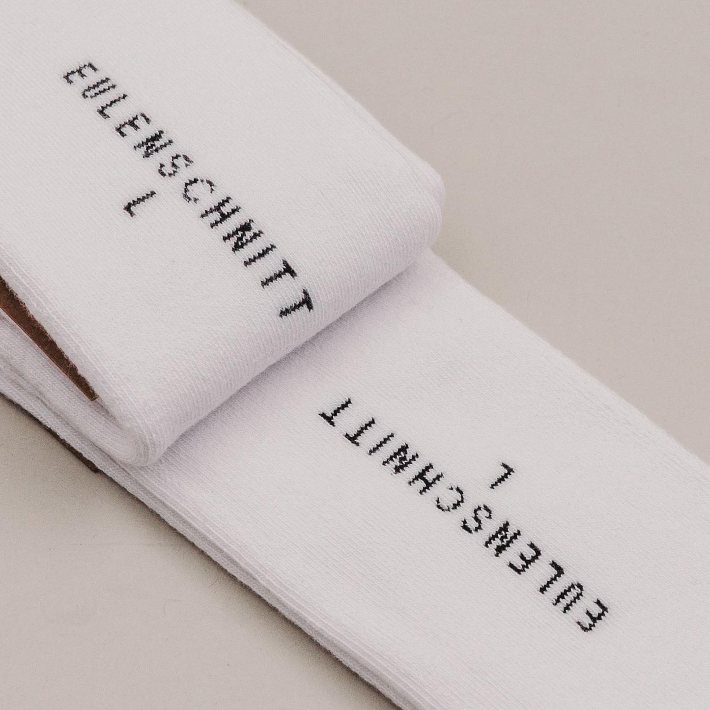 Gefaltete weiße Socken „MR“ mit Eulenschnitt Branding im Detail und der Größe L