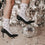 Weiße Socken mit schwarzen Herzen und schwarze High Heels in einer festlichen Szene mit großer Discokugel, silbernem Konfetti und glitzerndem Hintergrund.