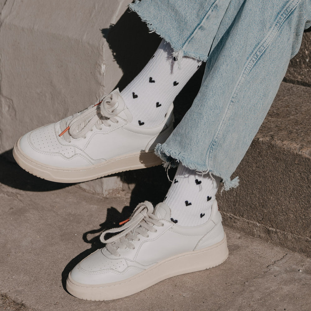 Detailaufnahme weißer Socken mit schwarzem Herzmuster und Sneakern im Alltag