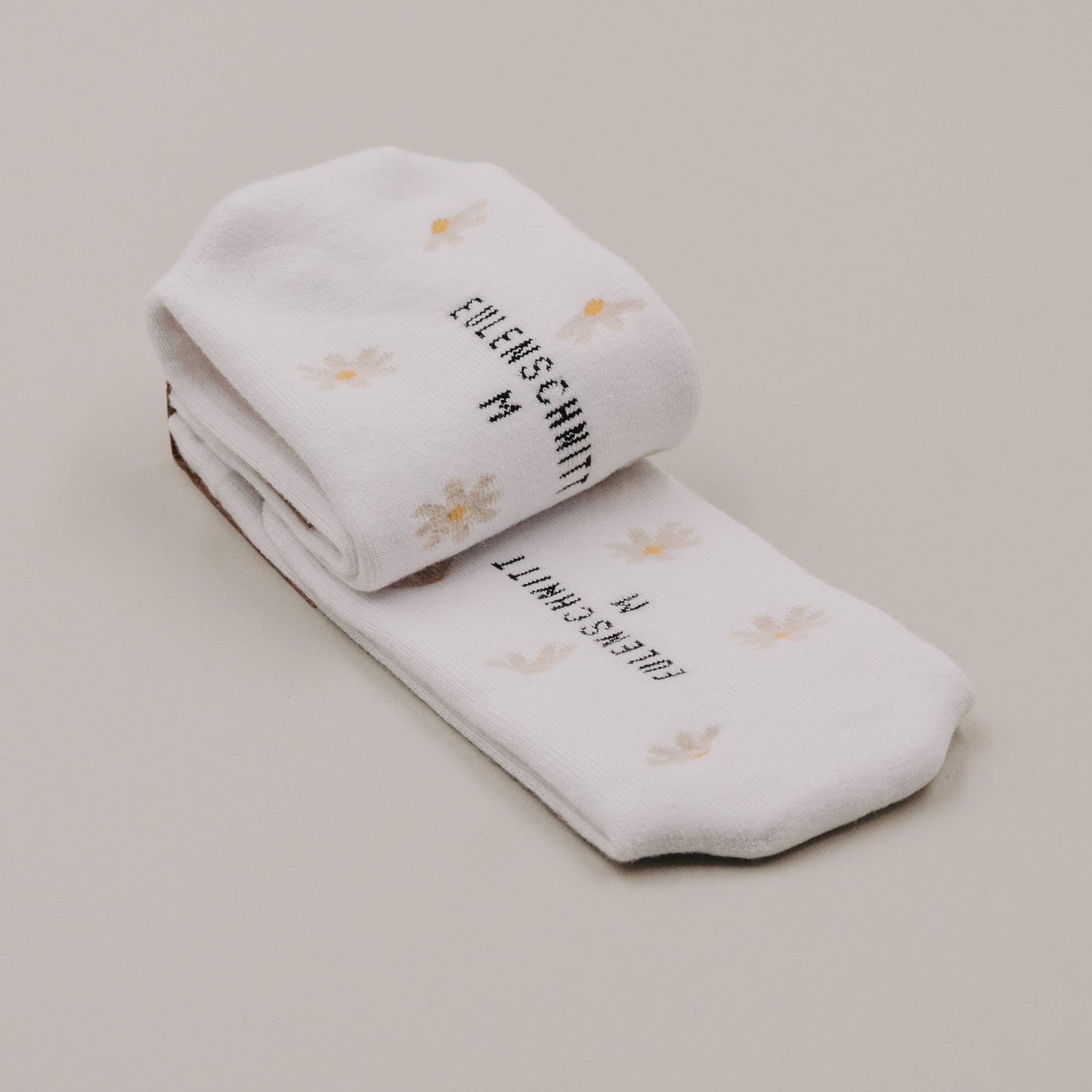 Gefaltete weiße Socken mit Daisy-Muster und Eulenschnitt Logo in Detailaufnahme