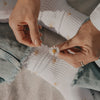 Weiße Socken mit Blumenmuster und Händen mit Gänseblümchen in stimmungsvoller Szene