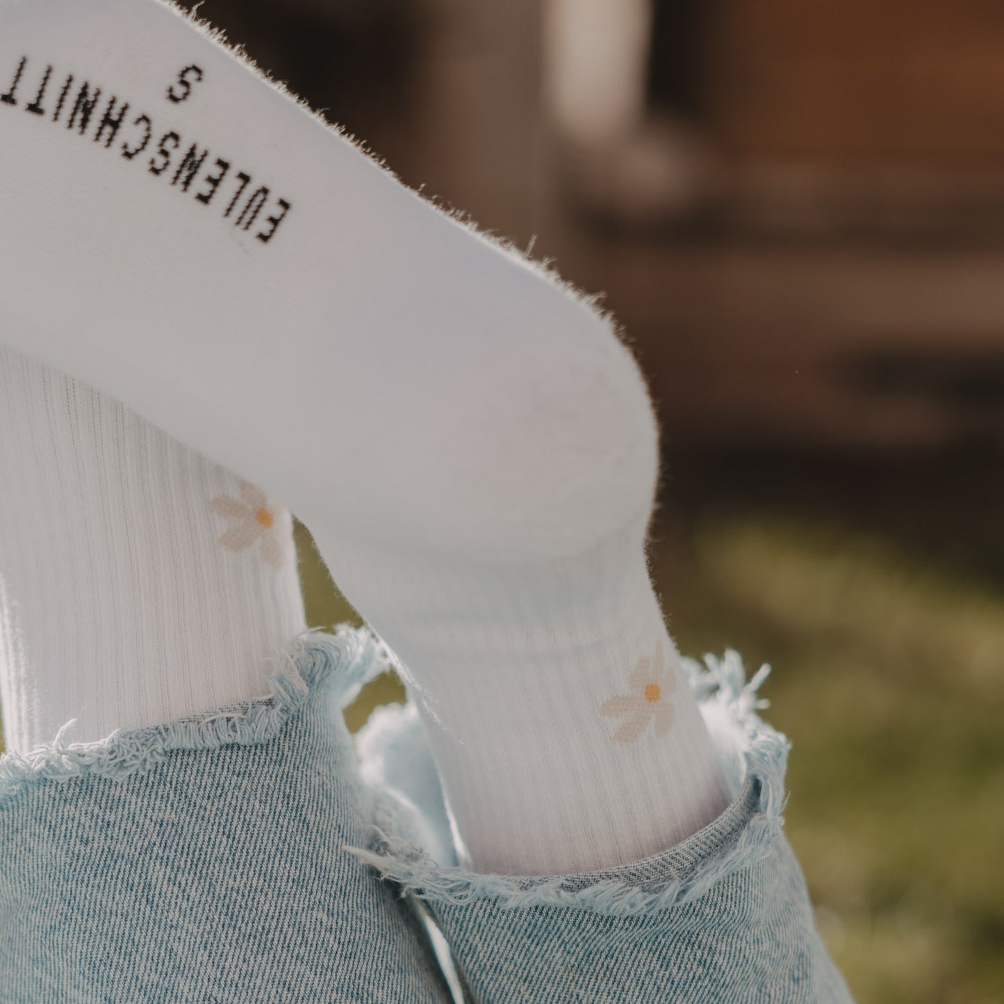 Detailansicht weißer Socken mit feinem Gänseblümchen-Motiv und Eulenschnitt Branding