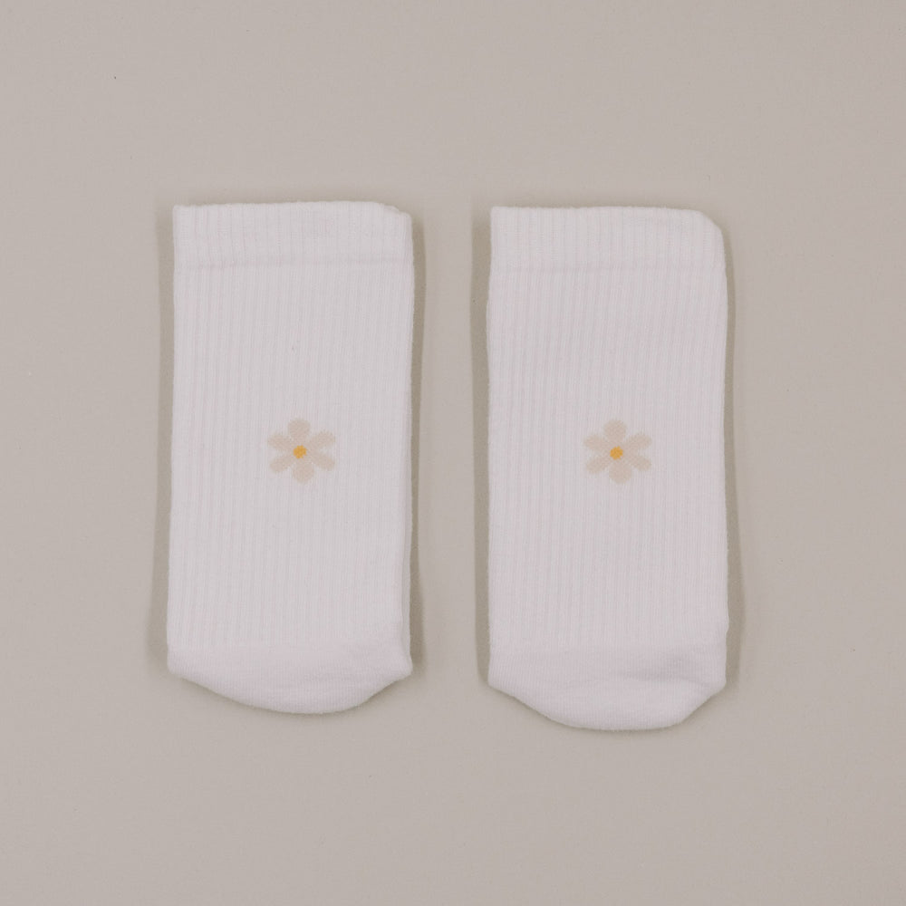 Minimalistische Produktansicht weißer Socken mit kleinem Daisy-Motiv auf hellem Hintergrund