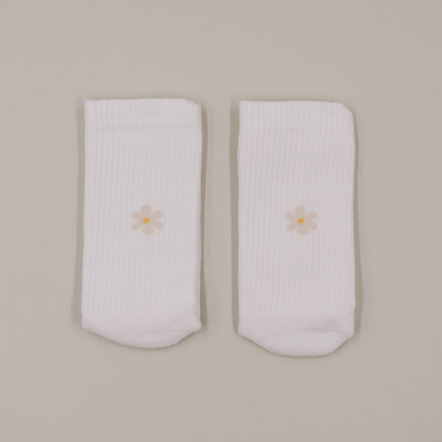Minimalistische Produktansicht weißer Socken mit kleinem Daisy-Motiv auf hellem Hintergrund
