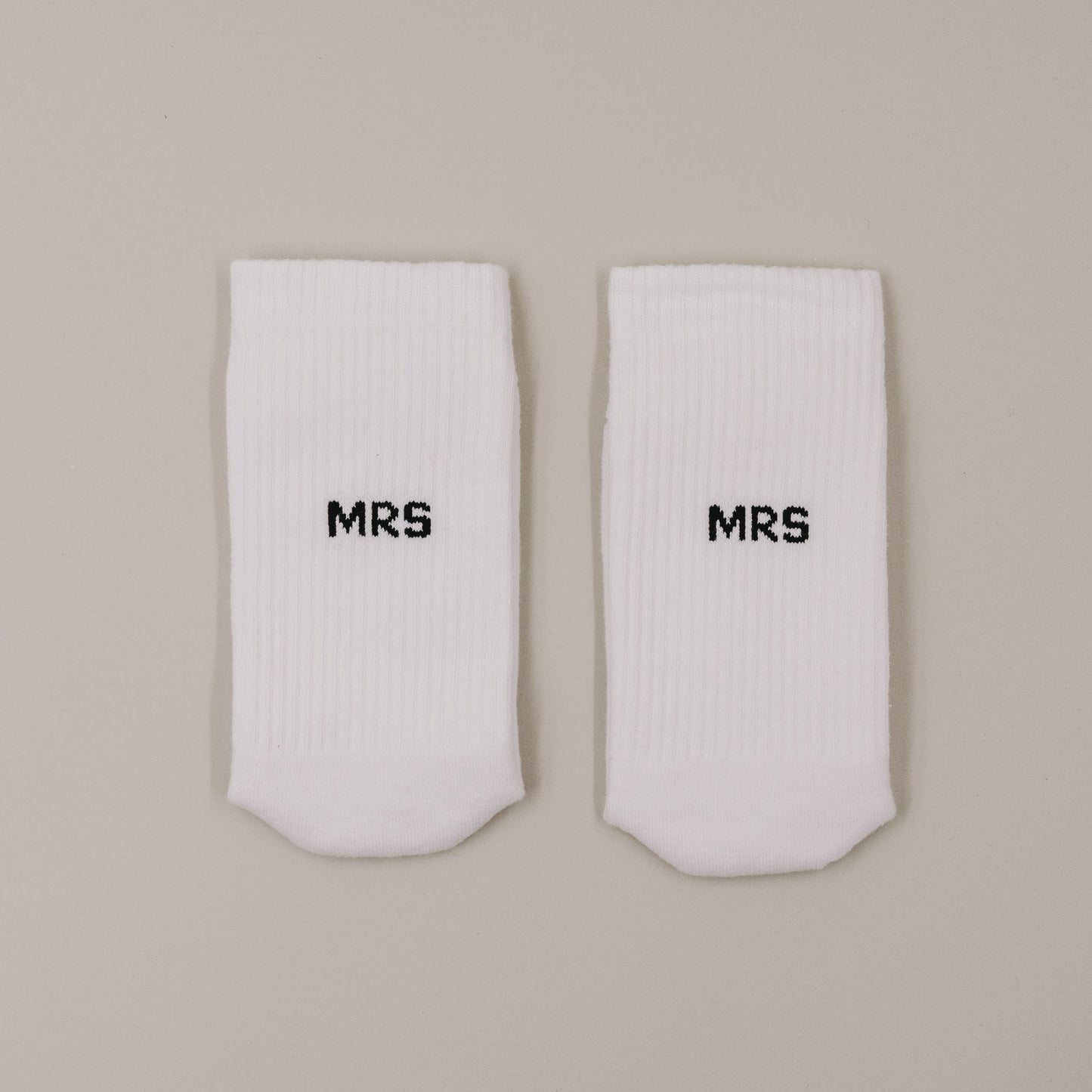 Flachliegende weiße Socken mit „MRS“ Schriftzug minimalistisch dargestellt