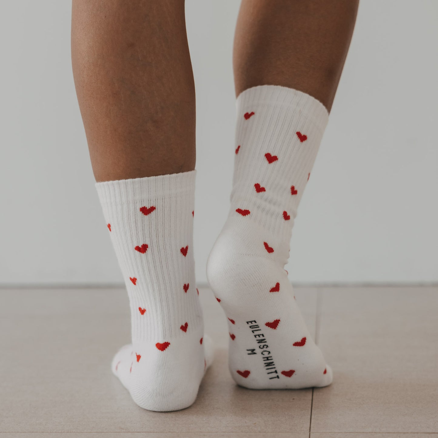 Weiße Eulenschnitt Socken mit roten Herzen und Logo auf der Sohle.