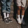 Zwei Kinder tragen weiße Eulenschnitt Socken mit roten Herzen und Sneaker.