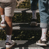 Zwei Kinder tragen Eulenschnitt Kindersocken mit roten Herzen beim gemeinsamen Treppensteigen.