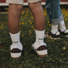 Kids Socken Großer Bruder in Weiß mit schwarzem Schriftzug zu Sneakern auf einer Wiese