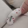 Nahaufnahme Babyfuß mit weißen Socken und roten Herzen, Sohle sichtbar