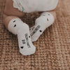 Baby trägt weiße Socken mit schwarzen Herzen, Sohle mit Schrift sichtbar