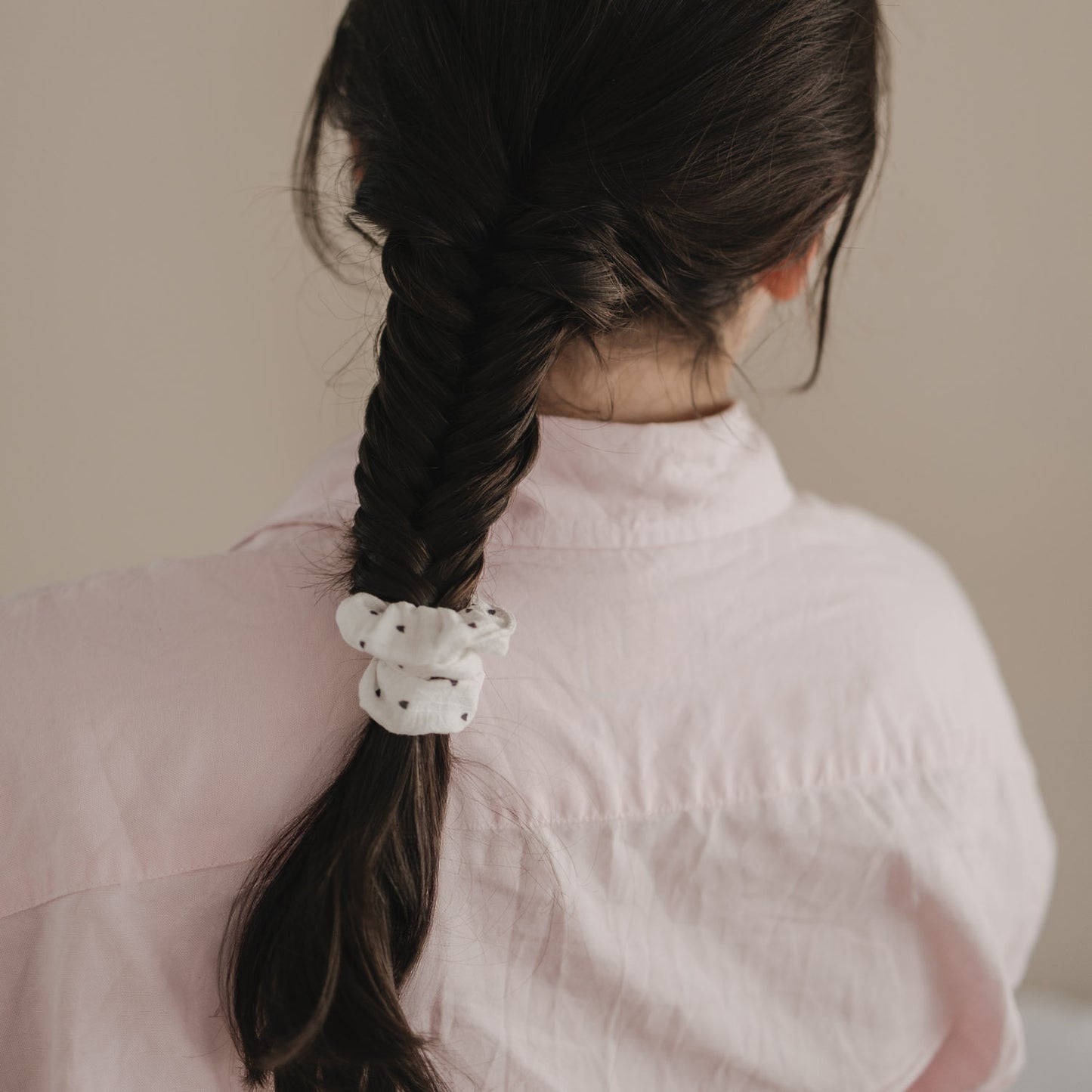 Geflochtener Zopf mit weißem Scrunchie mit schwarzen Herzen von hinten