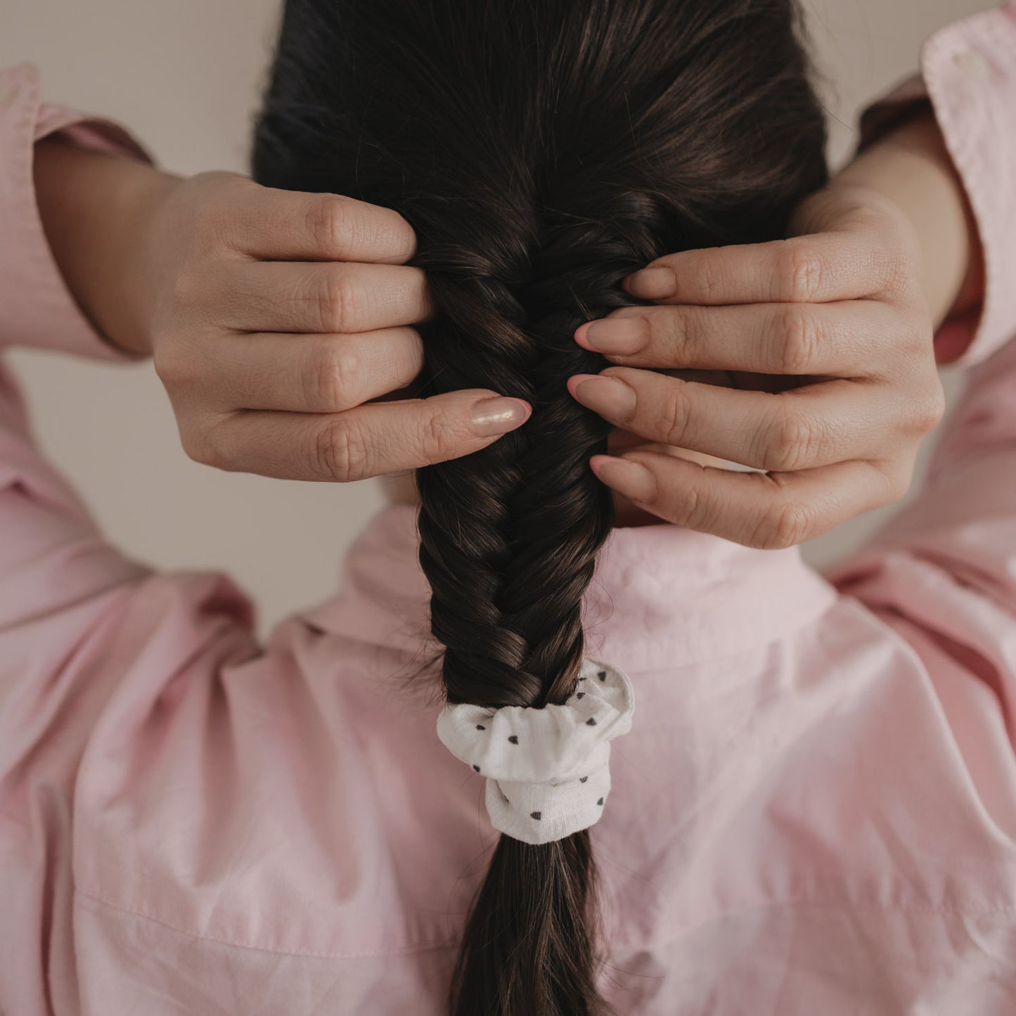 Hände stylen geflochtenen Zopf mit Scrunchie mit schwarzen Herzen