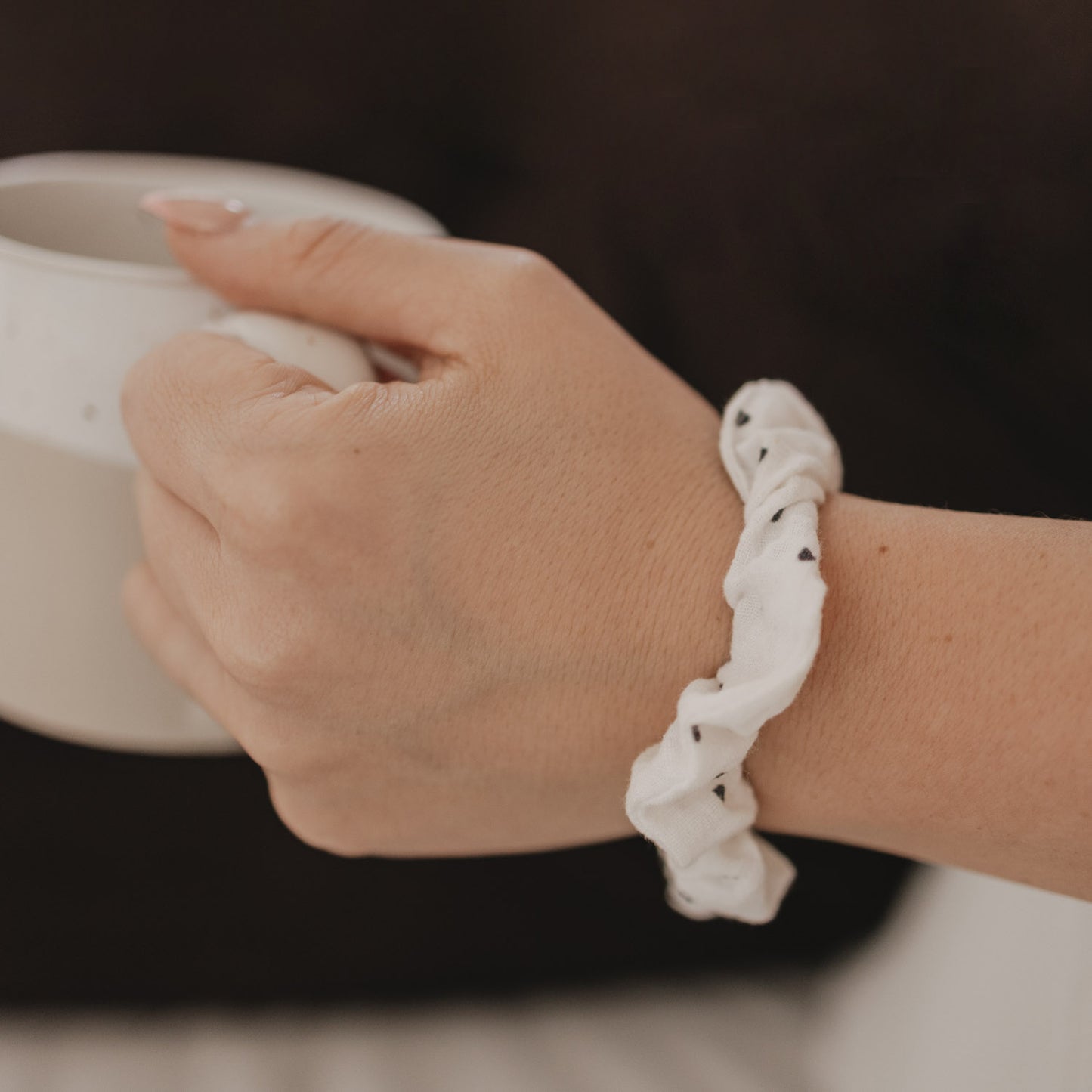 Detail Scrunchie mit schwarzen Herzen am Handgelenk mit Tasse