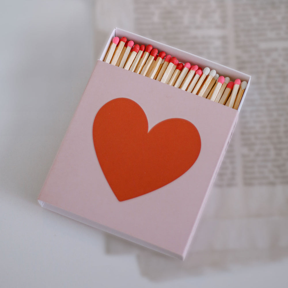 Offene Streichholzschachtel mit Herzdesign und farbigen Zündköpfen in Nahaufnahme.