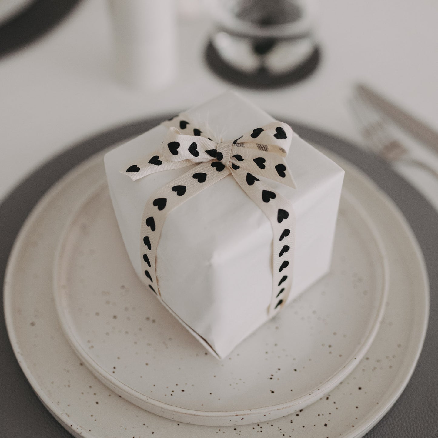 Geschenk mit Herz-Geschenkband als Tischdekoration gedeckt.