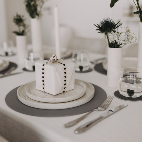 Gedeckter Tisch mit Geschenkband mit schwarzen Herzen als Highlight.