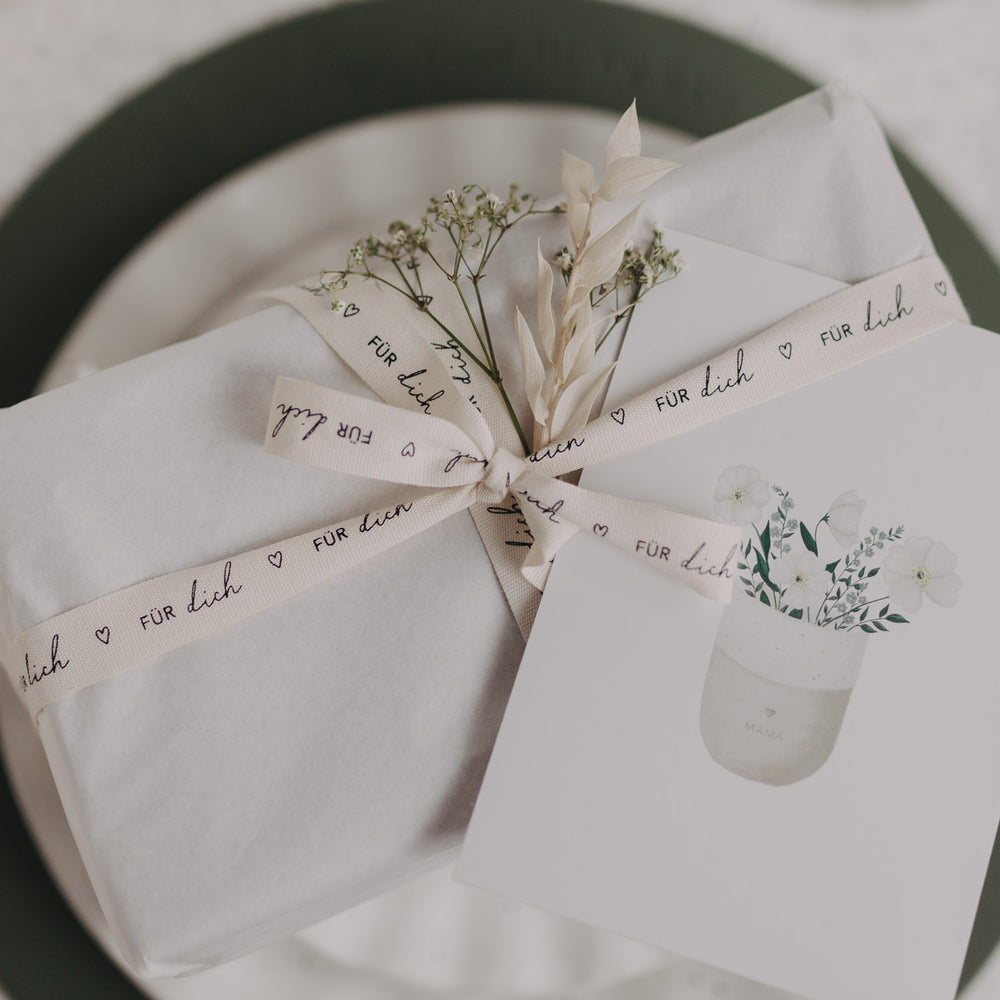 Verpacktes Geschenk mit Geschenkband „Für dich“ und Trockenblumen.