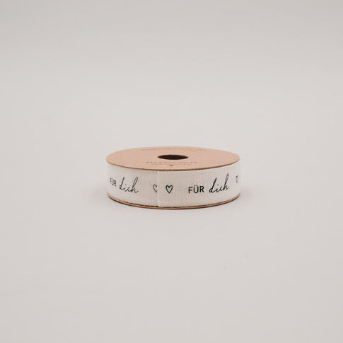 Seitliche Ansicht der Geschenkband-Rolle „Für dich“ mit schwarzem Schriftzug und Herzen auf hellem Band.