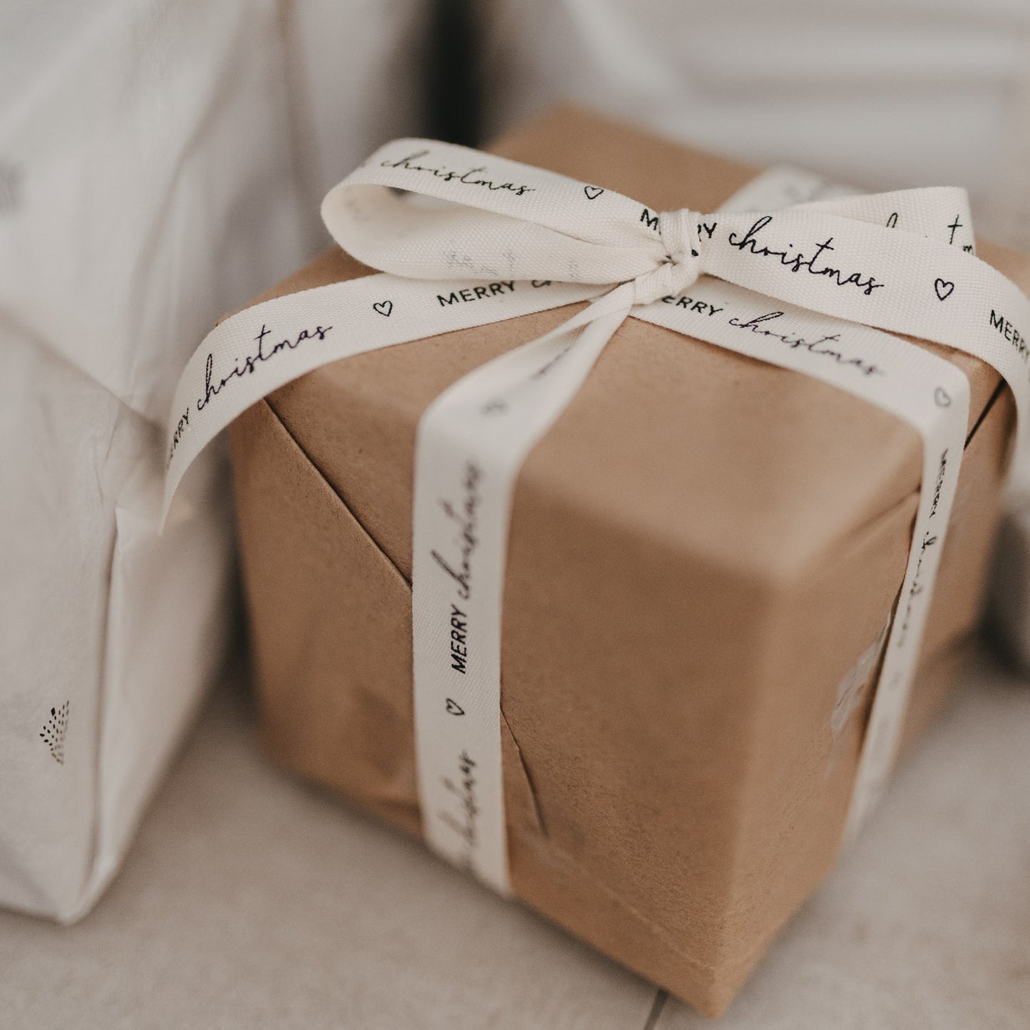 Nahaufnahme Geschenkband Merry Christmas um braunes Geschenkpapier gewickelt