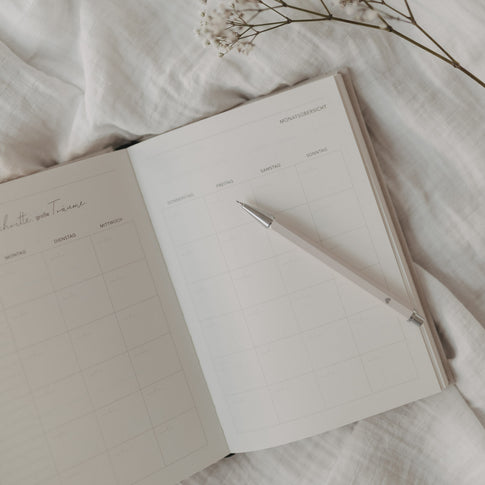 Druckbleistift Creme auf offenem Monatsplaner, dekorativ arrangiert.