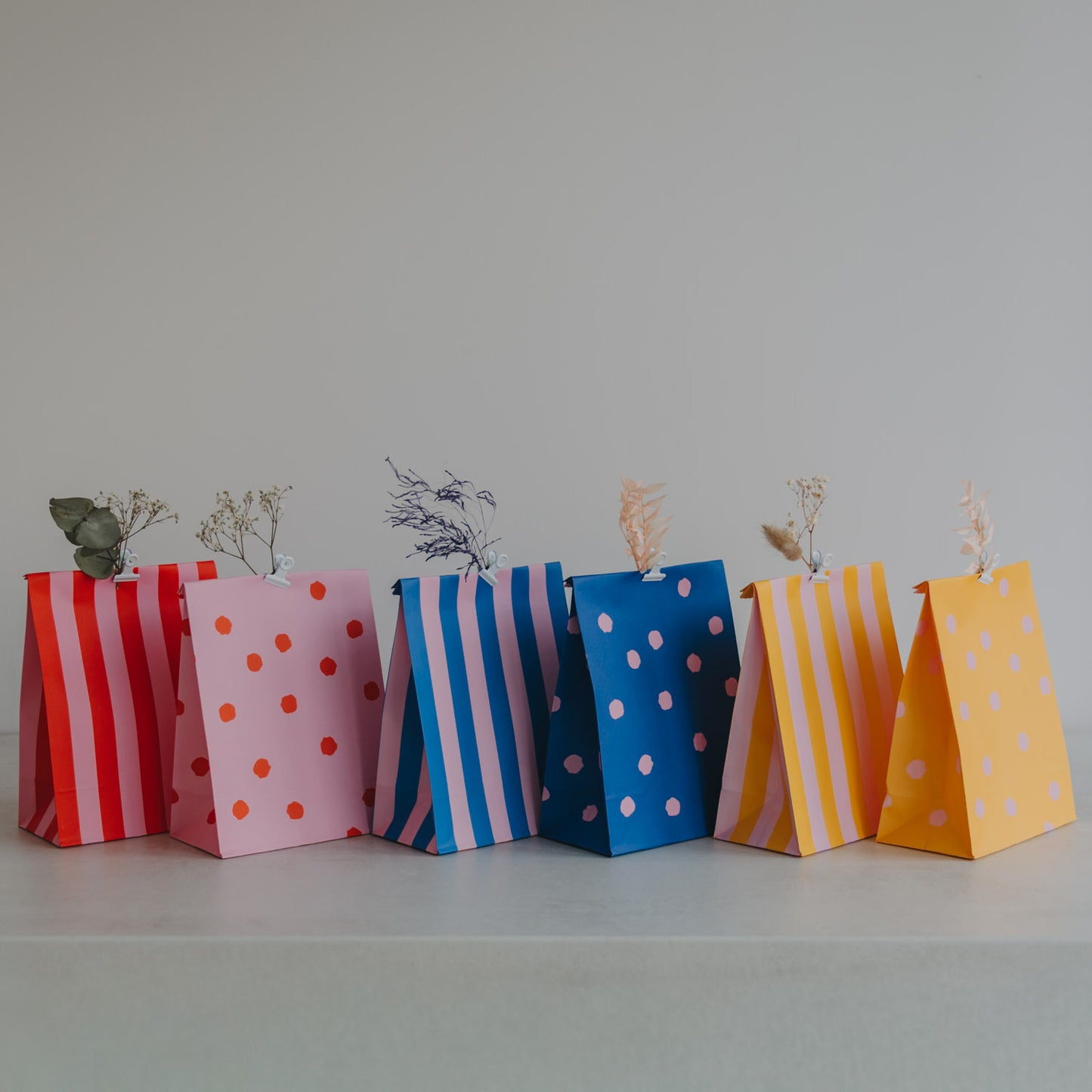 Bunte Geschenktüten aus Papier mit Streifen- und Punktmuster, dekorativ aufgereiht, ideal zum Verschenken