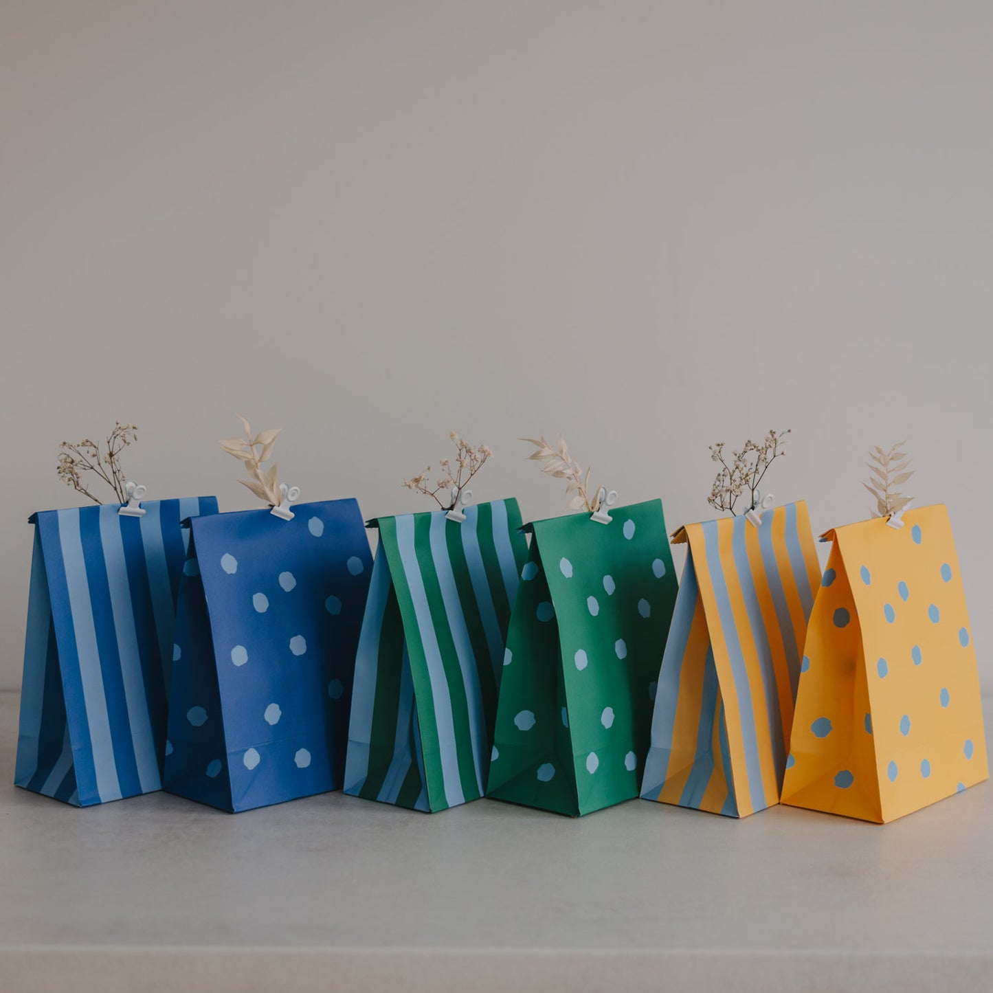 Bunte Papiertüten im 6er Set in Blau, Grün und Gelb mit Punkten und Streifen, dekorativ nebeneinander aufgestellt