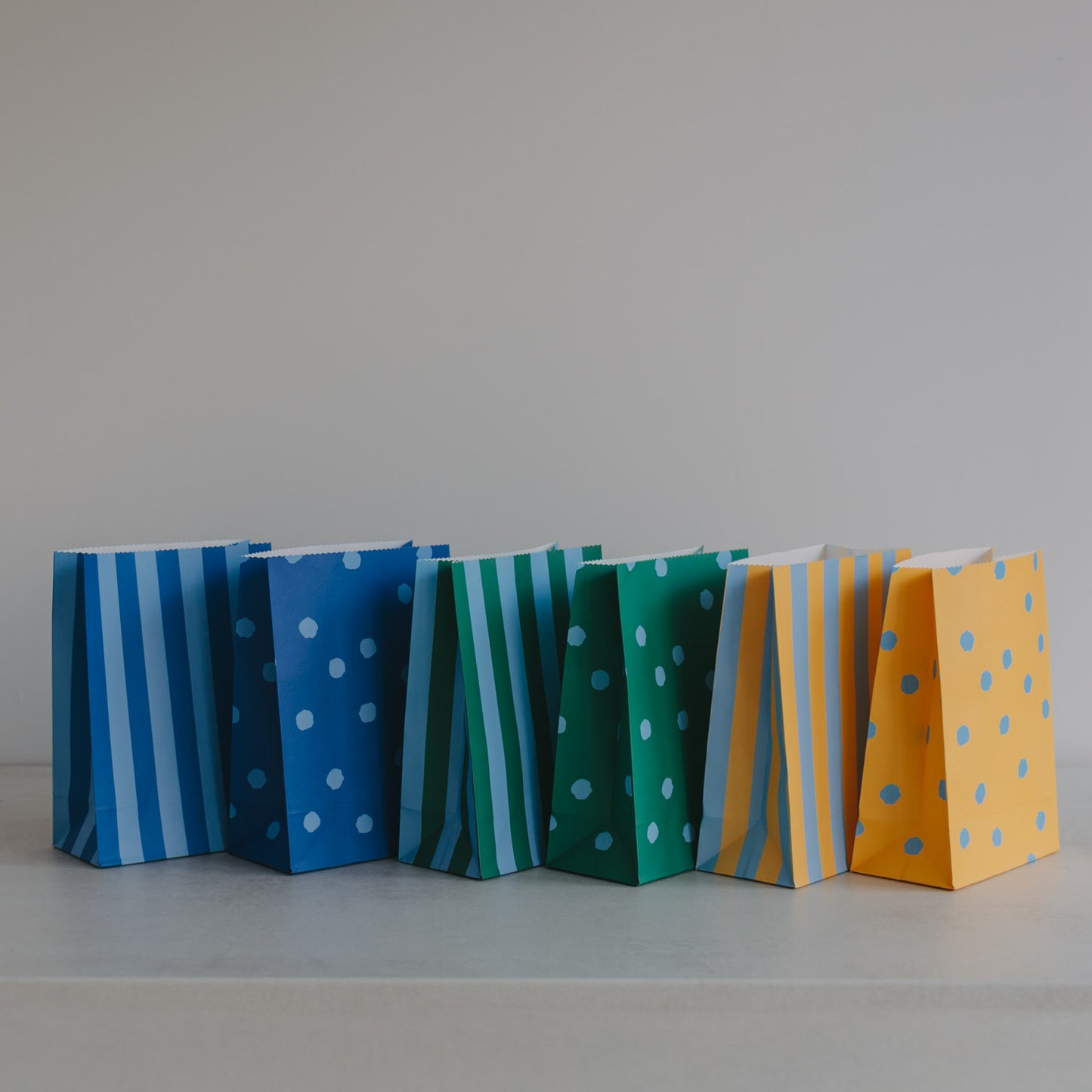 Papiertüten 6er Set in Blau, Grün und Gelb mit Punkten und Streifen, frontal nebeneinander