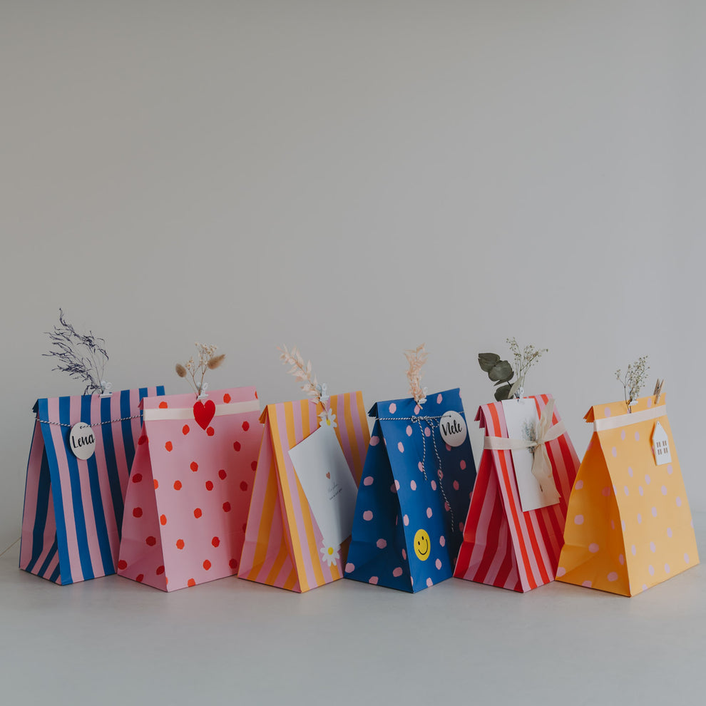 Bunte Geschenktüten aus Papier im 6er Set mit Streifen- und Punktdesign, dekoriert mit Trockenblumen.