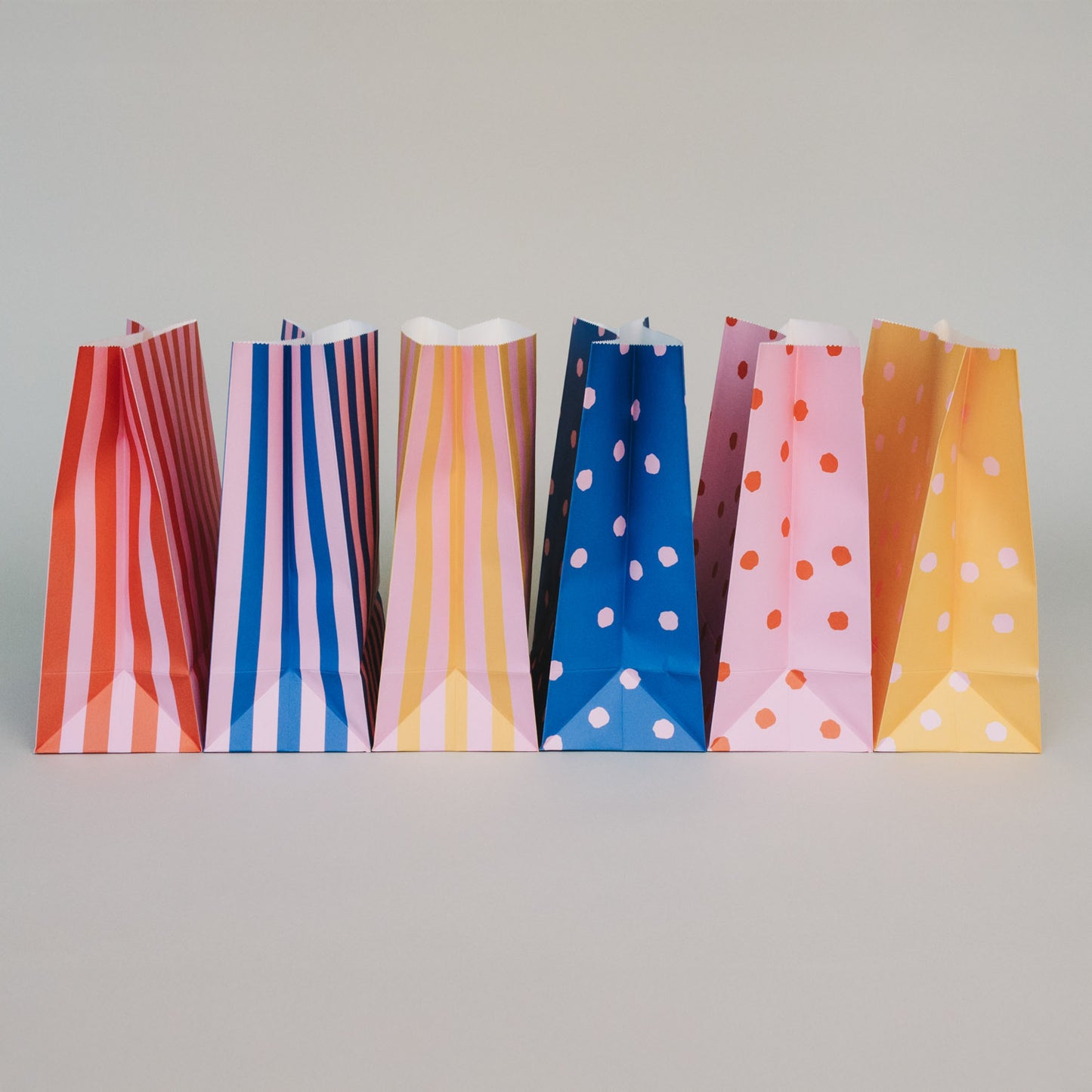 Seitenansicht bunter Geschenktüten aus Papier mit Streifen und Punkten im modernen Farbdesign.