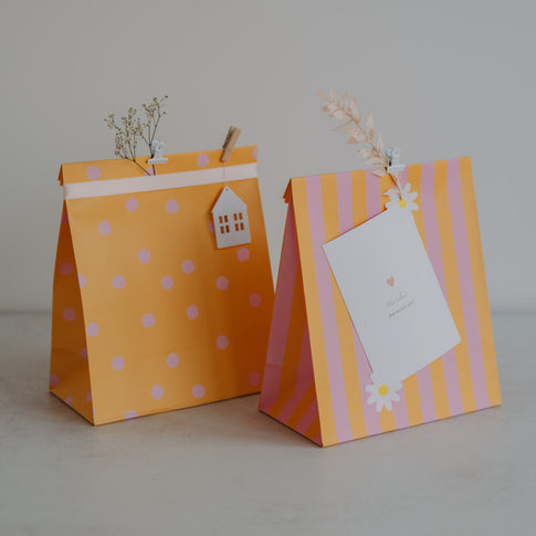 Geschenktüten aus Papier in Gelb und Rosa mit Punkten und Streifen, liebevoll dekoriert mit Anhängern.