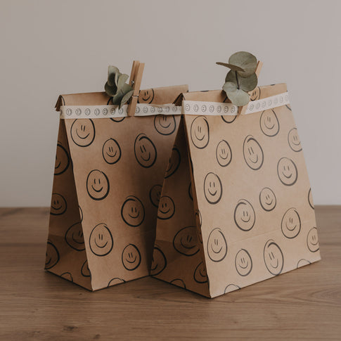 Geschenktüten aus Papier mit Smiley-Print, gefaltet und mit Trockenblumen dekoriert