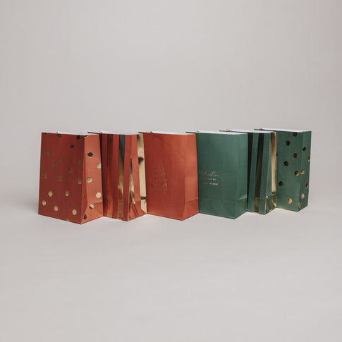 Rückansicht weihnachtlicher Geschenktüten aus Papier in Grün und Rot mit goldenen Akzenten