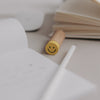 Radiergummi Smiley in Gelb auf Schreibtisch neben Notizbuch und Bleistift