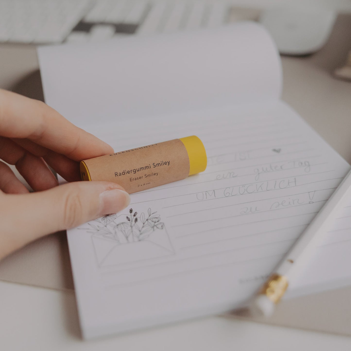 Radiergummi Smiley mit Papierhülle wird über liniertes Notizpapier gehalten