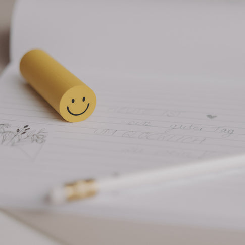 Radiergummi Smiley in Gelb auf Notizblock und Stift