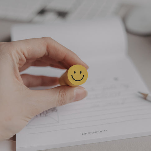 Radiergummi Smiley wird in der Hand gehalten vor Notizblock