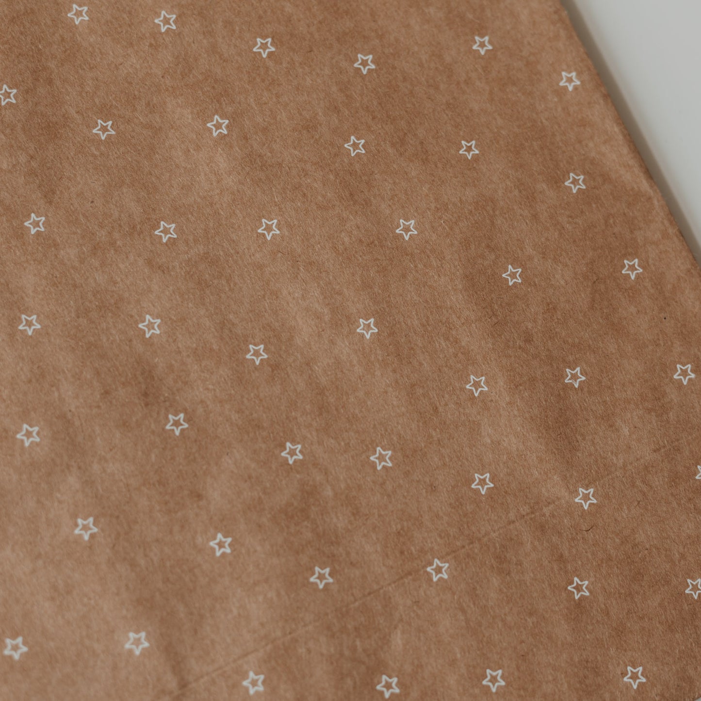 Detailansicht von Kraftpapier-Geschenktüte mit kleinem weißen Sternenmuster