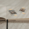 Detailansicht eines offenen Buchs mit Blankoseiten, Fotos und goldenen Stickern